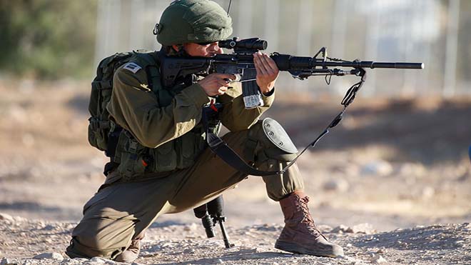 جندي اسرائيلي يصوب بندقيتة في اتجاه المتظاهرين الفلسطيينيين في قرية فصايل في وادي الاردن 
